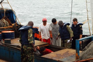 Portuguese naval officers and Gabonese sailors inspect a holding bay for fish aboard an illegal fishing vessel.